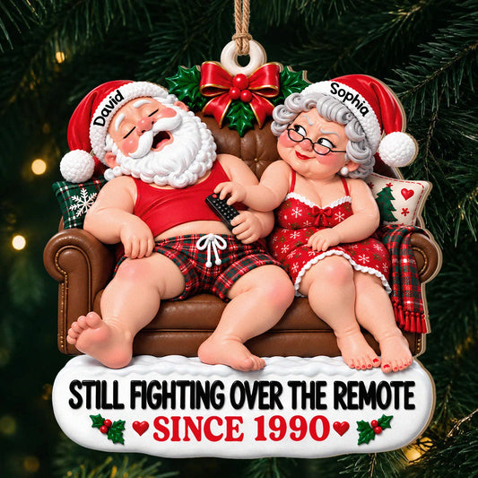 Personalisierter „Still Fighting Over the Remote“ Weihnachtsschmuck aus Holz für Paare – Rote Schlafanzüge, auf dem Sofa sitzend, Jubiläumsgeschenk für Paare
